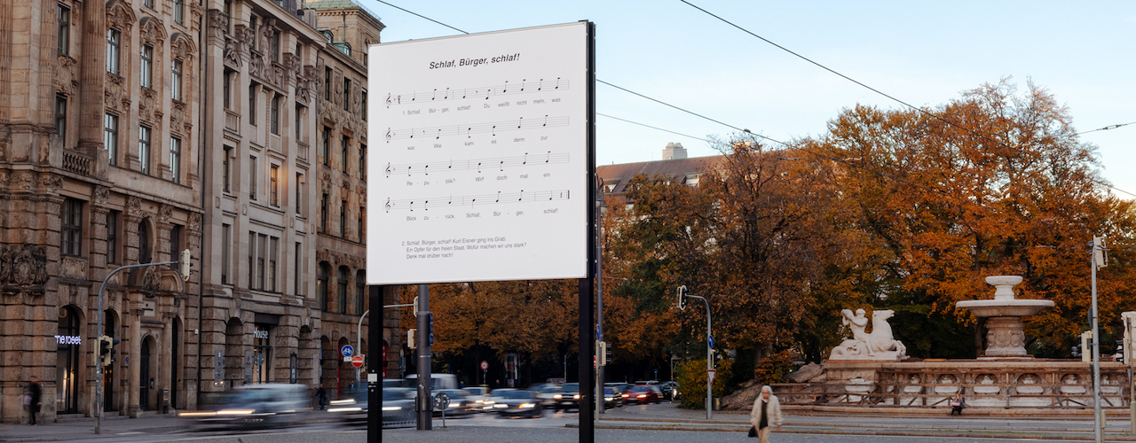 Fotografie des Lenbachplatzes mit diagonaler Ansicht der stadteinwärts weisenden Seite des Billboards.